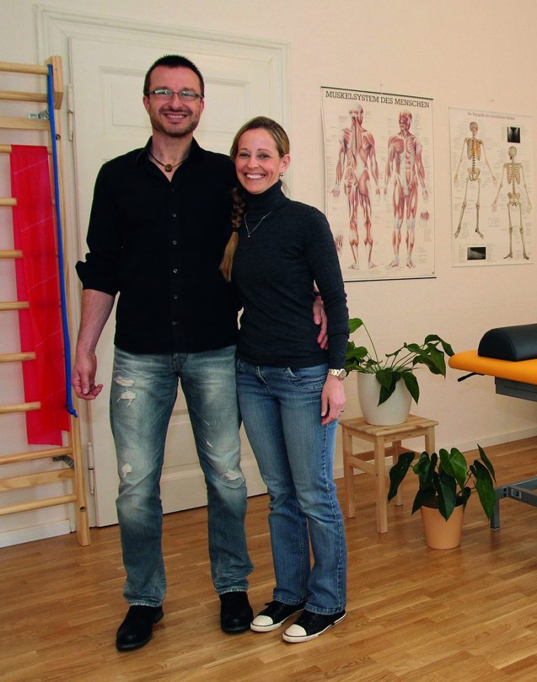 Sven Michael und Eva Anstatt bei der Praxiseröffnung Sven Michael und Eva Anstatt auf einer kleinen Treppe vor dem Praxiseingang und dem Praxis-Schild.